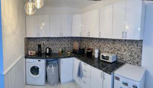 cocina con armarios blancos, lavadora y secadora en Midtown Apartment en Kŭrdzhali
