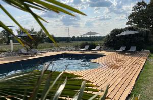 a pool with chairs and umbrellas on a wooden deck at La Grange de La Dupuise in Civrac-de-Blaye