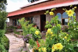 un jardín frente a una casa con flores en TAQUILE LODGE - Un lugar de ensueño en Huillanopampa