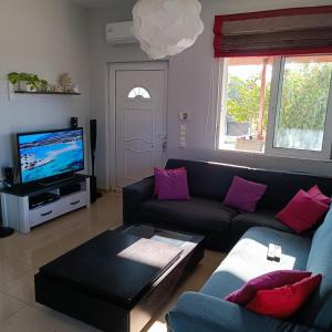 uma sala de estar com um sofá e uma televisão em Drosoula Villa 3bdr private swimming pool em Chorafakia