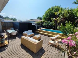 a deck with chairs and a table and a pool at Maison de ville 6 couchages au centre de Lège bourg in Lège-Cap-Ferret