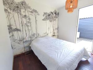 a bedroom with a bed with a mural of trees on the wall at Maison de ville 6 couchages au centre de Lège bourg in Lège-Cap-Ferret