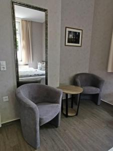 um quarto com um espelho, uma cadeira e uma mesa em Pension Ginko em Wernigerode