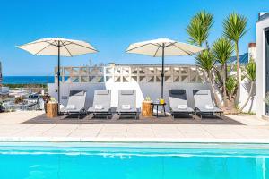 a group of chairs and umbrellas next to a pool at Portugal Active Sunset Beach Lodge in Carreço