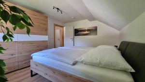 een slaapkamer met een groot bed en een houten muur bij Ferienwohnungen Rabensteiner in Bad Kleinkirchheim