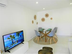 een woonkamer met een tv en een tafel en stoelen bij Carvoeiro Boutique Apartment in Carvoeiro
