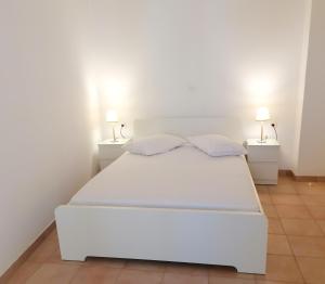 a white bed in a white room with two lamps at Kefalonia, Lixouri family friendly house & parking in Lixouri