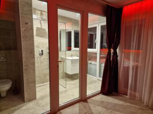 a bathroom with sliding glass doors and a toilet at Rooms Green Set in Belgrade