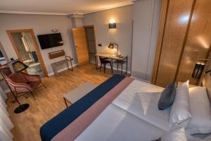 a bedroom with a large bed and a living room at Hotel Castilla Vieja in Palencia