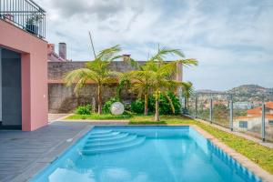 a swimming pool in the backyard of a house with palm trees at Villa Vacuna in Funchal