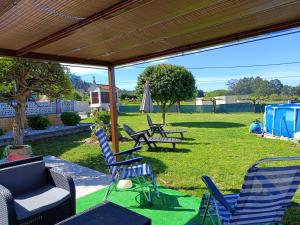a patio with chairs and tables and an umbrella at Casa/chalet en Sanxenxo 3hab. in Sanxenxo