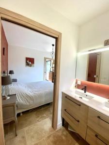 ein Bad mit einem Bett, einem Waschbecken und einem Spiegel in der Unterkunft Spacieuse villa, environs 10 min à pied des plages in La Garde