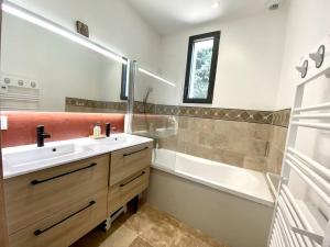 ein Badezimmer mit einem Waschbecken, einer Badewanne, einem Waschbecken und einem Spiegel in der Unterkunft Spacieuse villa, environs 10 min à pied des plages in La Garde