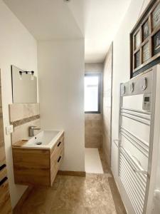 ein weißes Badezimmer mit einem Waschbecken und einem Kühlschrank in der Unterkunft Spacieuse villa, environs 10 min à pied des plages in La Garde