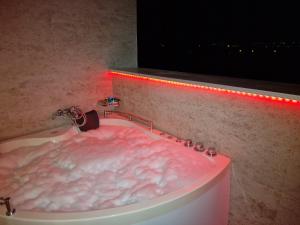 a bathroom with a pink bath tub with a red light at Rooms Green Set in Belgrade
