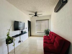 sala de estar con sofá rojo y TV en Depa Xcalacoco, Playa Del Carmen en Playa del Carmen