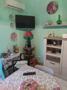 sala de estar con mesa y TV en la pared en Cottage Gole Alcantara holiday Pafumi, en Graniti