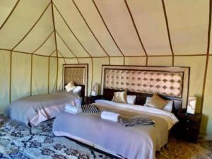 a room with two beds in a tent at Desert Coast Opulent Camp in Merzouga