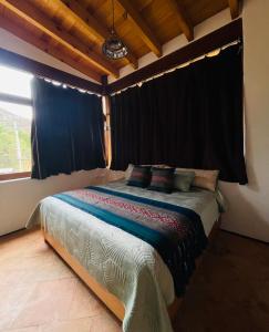 een slaapkamer met een bed met zwarte gordijnen en een raam bij Casa IxeYolo in Amatlán
