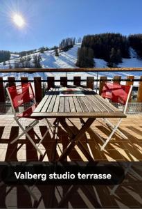 una mesa de madera y sillas en una terraza con nieve en Alpazur-studio départ pistes, en Péone