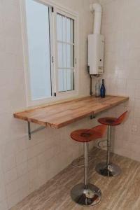 una cocina con 2 taburetes y una barra con ventana en Gran casa con piscina centro de sevilla Vistas, en Sevilla