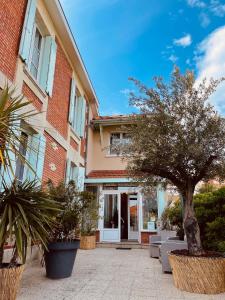 a building with a tree and chairs in front of it at Hôtel Michelet Plage in Soulac-sur-Mer