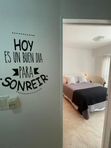a bedroom with a bed with a sign on the wall at Gerbera Colorada HAEDO in Mariano J. Haedo