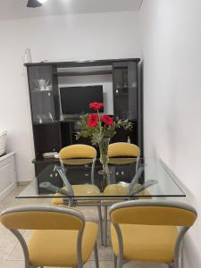 una mesa de cristal con sillas amarillas y un jarrón con flores en Gerbera Colorada HAEDO en Mariano J. Haedo