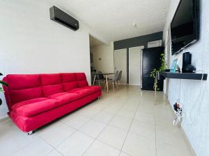 un sofá rojo sentado en una sala de estar en Depa Xcalacoco, Playa Del Carmen en Playa del Carmen