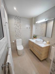 uma casa de banho com um lavatório, um WC e um espelho. em Apartamento vistas al mar de La Pineda! em La Pineda