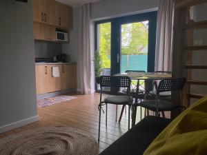 Una sala de estar con mesa y sillas y una cocina. en Dom Wypoczynkowy Zacisze- klimatyczny domek z kominkiem, en Stegna