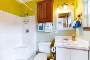 a bathroom with a toilet and a sink and a mirror at Our Happy Place in Rockaway Beach +18 photos