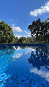 a blue swimming pool with trees in the background at Espaço Benviver in Guaratinguetá