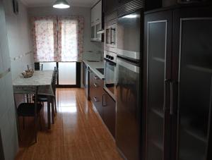 a kitchen with a stainless steel refrigerator and a table at Apartamento Río Breiro in Boiro