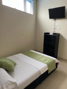 Hotel el Turista في فلورنسيا: غرفة نوم صغيرة بها سرير وتلفزيون