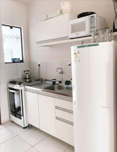 een keuken met witte kasten en een witte koelkast bij Residencial COLIBRI in Garopaba