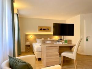 a hotel room with a bed and a desk with a tv at Hotel Bronnbacher Hof in Wertheim