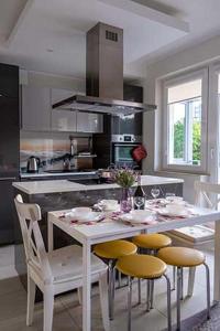 a kitchen with a table with yellow chairs and a kitchen with a stove at Apartament Alma in Gdańsk