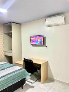 a bedroom with a desk and a tv on the wall at Apartamento Studio Centro in Macapá