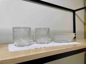 two glass mugs and bowls on a shelf at Apartamento Studio Centro in Macapá
