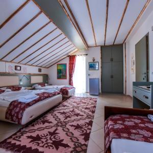 a hotel room with three beds and a rug at Oda`s Room in Sarandë