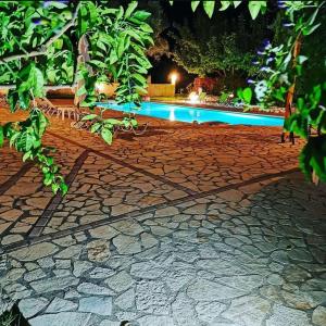 a stone walkway with a swimming pool at night at Calderimi Lefkada in Nydri