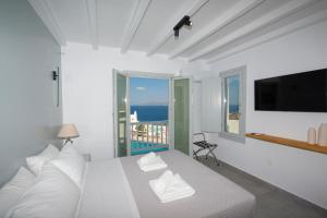a white bedroom with a bed and a television at Villa Orion Mykonos - Magnificent Sea View in Mýkonos City