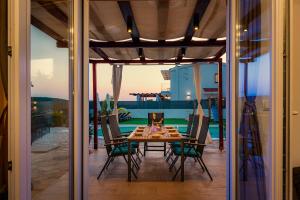 a dining table and chairs on a patio at Villa Plenča green sea near to the sea - heated pool in Šibenik