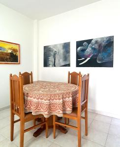 uma mesa de jantar e cadeiras com pinturas na parede em sea & sun apartment 1 em Durrës
