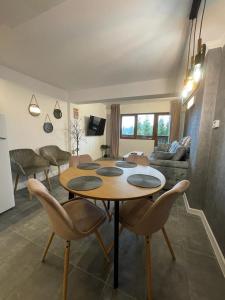 Harmony Apartment Poiana Brasov في بويانا براسوف: غرفة معيشة مع طاولة وكراسي خشبية