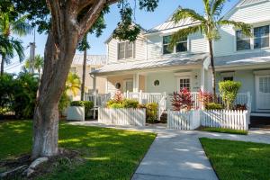 a white house with a fence and palm trees at Beach House Getaway in Duck Key