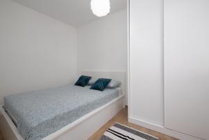 ein kleines Bett in einem weißen Zimmer mit blauen Kissen in der Unterkunft Apartment KriLa in Kaštela