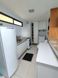 a kitchen with white counters and a refrigerator at Loft Luxor Tambaú in João Pessoa