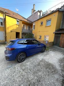 une voiture bleue garée devant une maison dans l'établissement Appartement Familiale PREMIUM : proche gare de Belfort, à Belfort